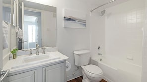 Un bany amb un lavabo blanc, un mirall, un vàter i una banyera.