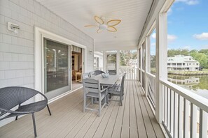 A covered outdoor area with a table and chairs, a ceiling fan, and a view of a body of water and buildings.