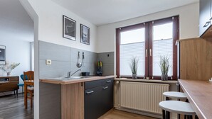 Une cuisine moderne avec un plan de travail en bois, des meubles de couleur noire et une fenêtre équipée de stores.