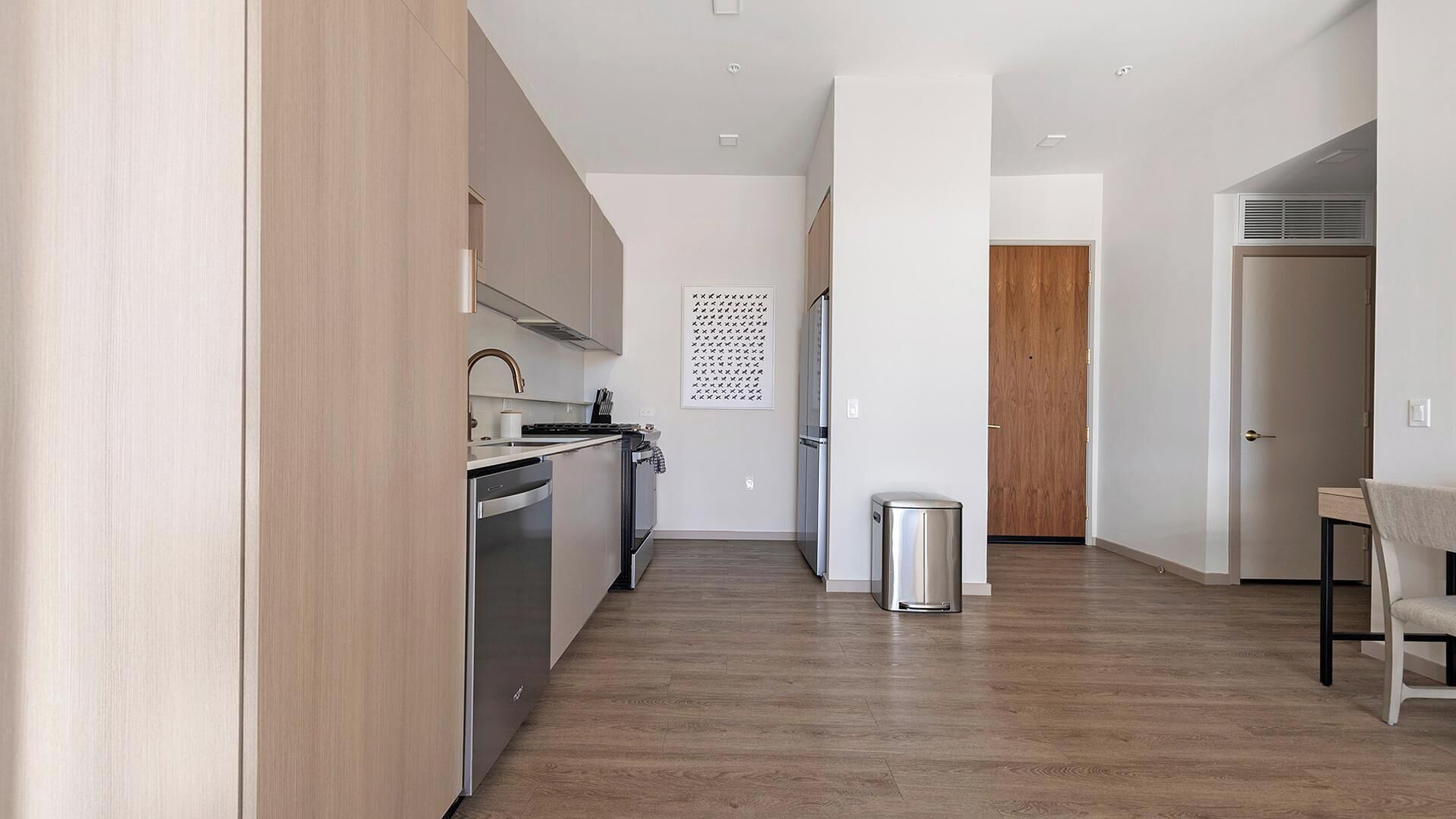 Una cucina moderna con elettrodomestici in acciaio inossidabile, pavimento in legno e design minimalista.