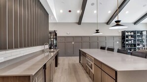 A modern kitchen with a large island, wooden cabinets, and pendant lighting. - Landing | Chic 1BD, Pool, Clubhouse (Willow Springs)