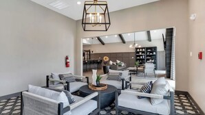 A modern lounge area with sofas, a coffee table, and a bookshelf. - Landing | Chic 1BD, Pool, Clubhouse (Willow Springs)