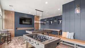 Een moderne kamer met een tafelvoetbaltafel, een bar en een zite hoek.