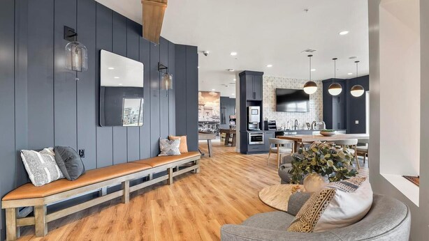 Een moderne woonkamer met een houten bank, een grijze bank en een eethoek met een tafel en stoelen.