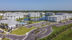 A modern apartment complex with a central courtyard, a swimming pool, and a parking lot.