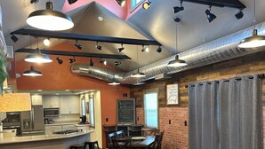 Una cocina moderna con electrodomésticos de acero inoxidable, una barra con taburetes, un sofá de cuero y una mesa de comedor.