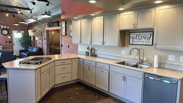 A modern kitchen with white cabinets, a built-in dishwasher, and a gas stove.