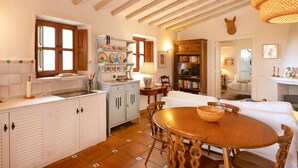 A cozy kitchen with white cabinetry, a wooden dining table, and a bookshelf. - La Cuadra in Frigiliana (Frigiliana)