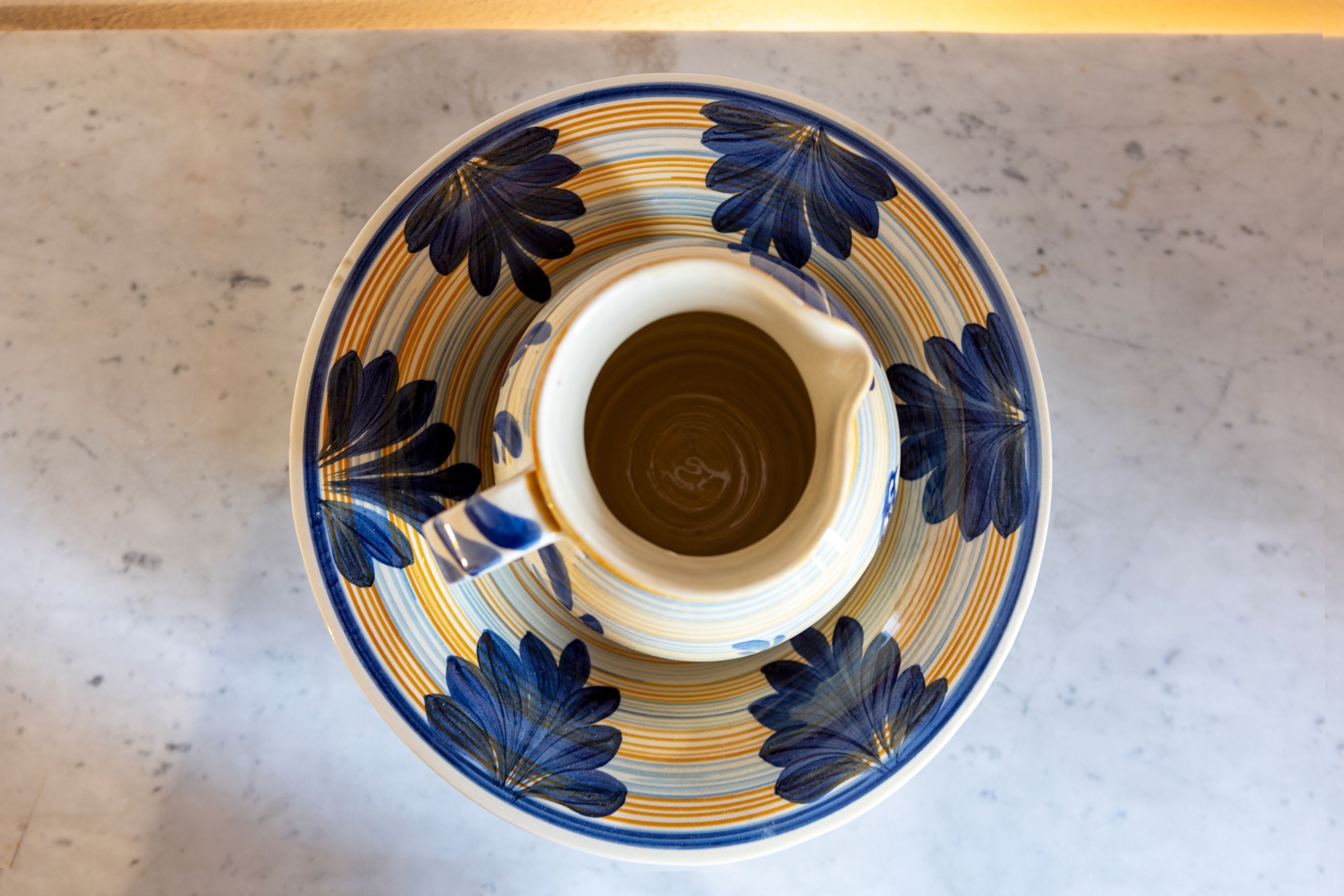 Une tasse en céramique ornée d’un motif floral, posée sur une surface en marbre.