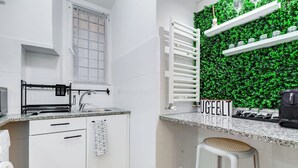 Een moderne keuken met witte kastjes, een ingebouwde oven, een spoelbak en een aanrecht met een koffiezetapparaat.