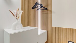 Een moderne badkamer met een witte wastafel, een wand van houten panelen en een zwarte handdoekhouder.