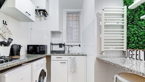 Een kleine keuken met een wasmachine, magnetron en een klein spoelgedeelte.