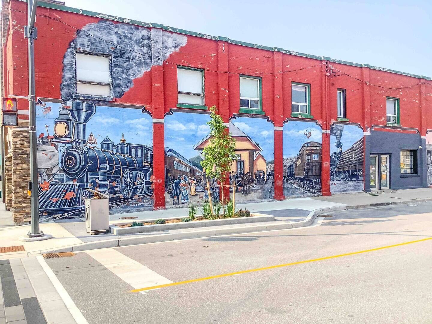 A mural on a red building depicting historical trains and scenes.