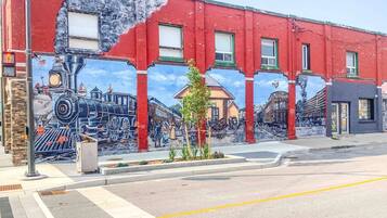 A mural on a red building depicting historical trains and scenes.
