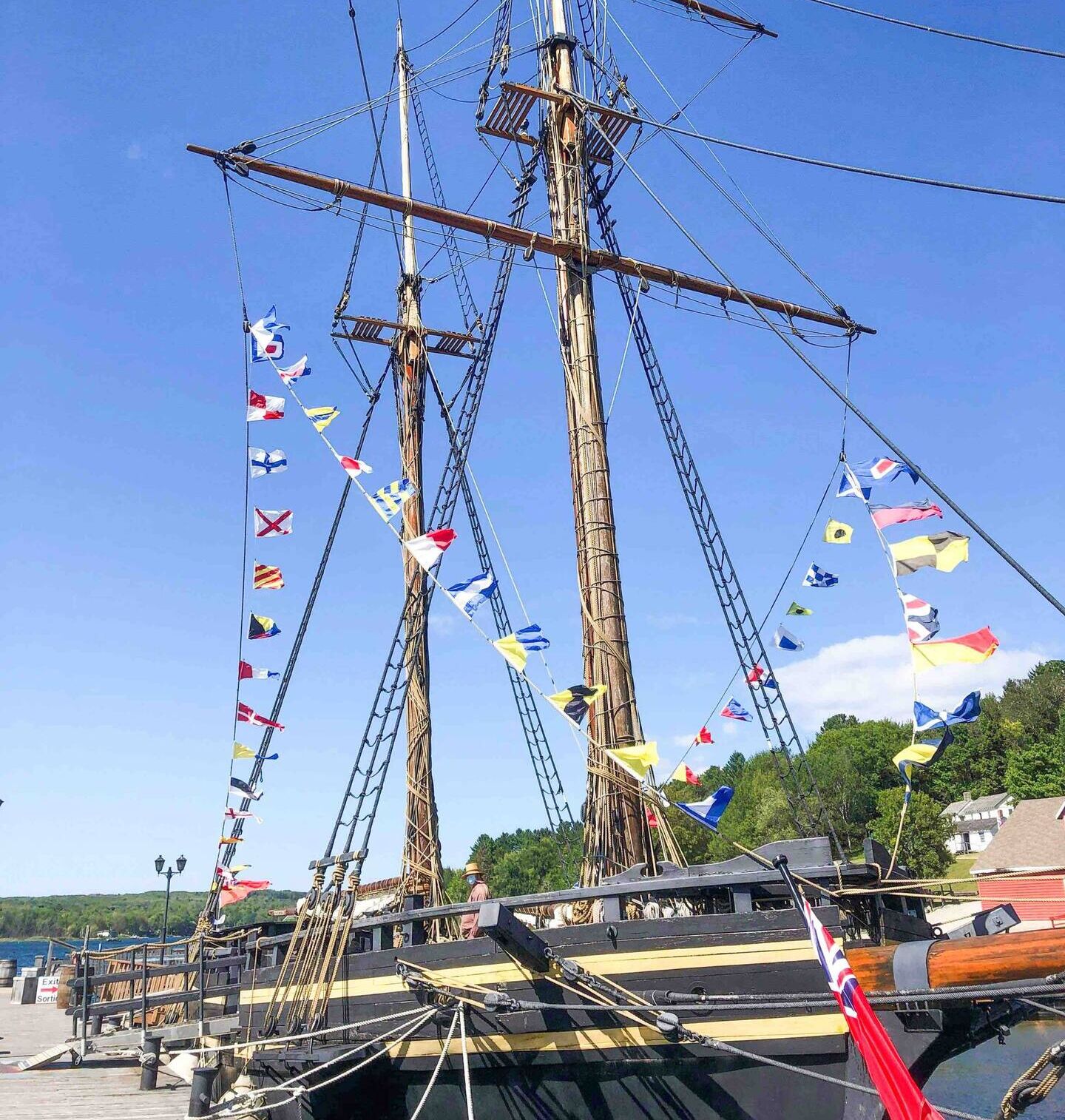 A tall ship docked at a pier with multiple flags.