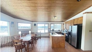 Una cocina amplia con armarios de madera, una isla central y un comedor con sillas.