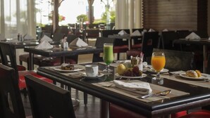 Un restaurante con mesas dispuestas para el desayuno, incluyendo platos de comida, bebidas y servilletas.