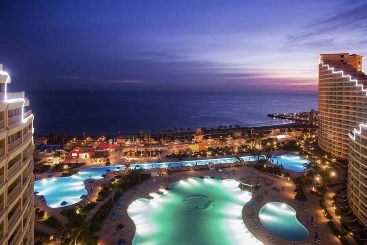 A resort with multiple swimming pools, beachfront views, and illuminated buildings.