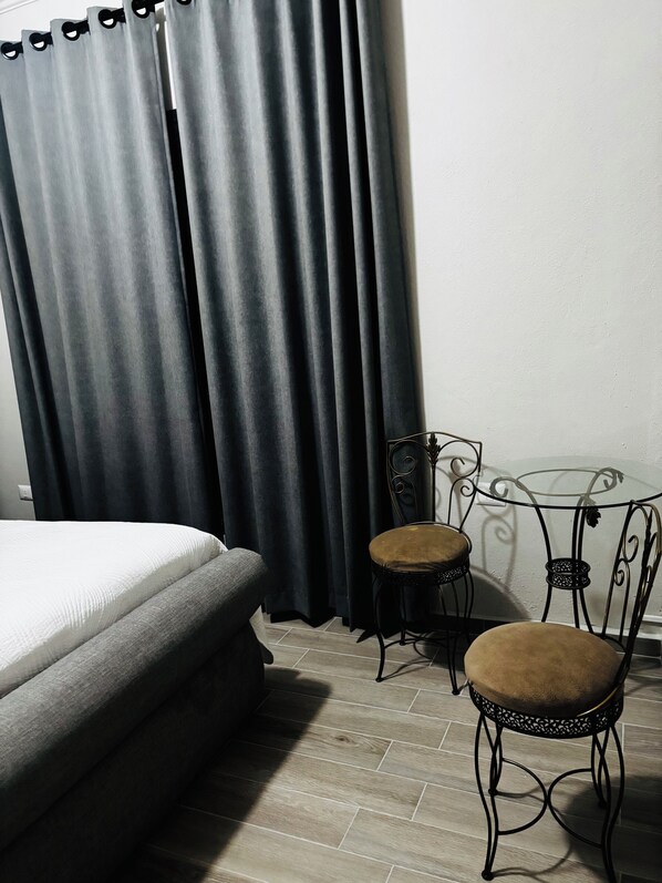 A room with a bed, two chairs, a small table, and a curtain. - Casa victoria hotel (Ezequiel Montes)