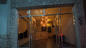 A stone facade with a glass entrance leading to an interior with a wooden reception desk and a chandelier. - Casa victoria hotel  (Ezequiel Montes)
