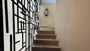 A staircase with a black metal railing and a fire extinguisher mounted on the wall. - Casa victoria hotel  (Ezequiel Montes)
