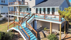 Una casa de dos pisos con un balcón, mobiliario exterior y una piscina.
