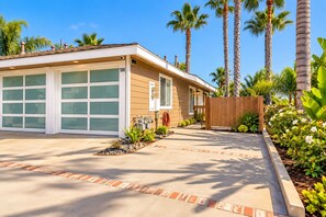A two-story house with a garage, a driveway, and a wooden fence. - Seaside Escape + Walk to Encinitas Beach + Wifi + Free Parking (Encinitas)