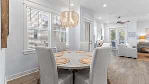 Un coin repas avec une table ronde, des chaises blanches et un lustre.
