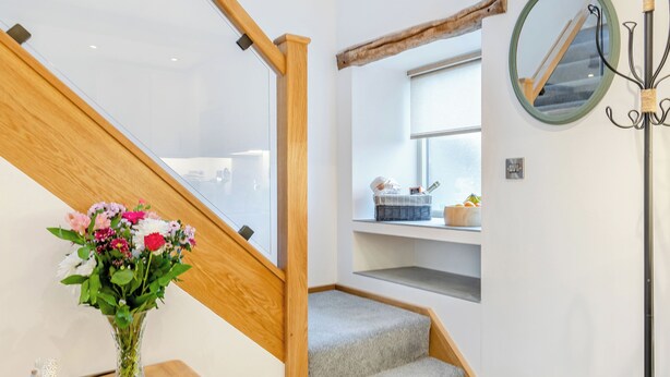 A staircase with wooden railings, a vase with flowers, and a mirror on the wall. - Clarence Cottage - UK47494 (Winkhill, near Leek)