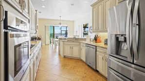 A modern kitchen with stainless steel appliances, white cabinetry, and a large island with a sink.