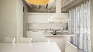 A modern kitchen with white cabinetry, a central island, and a hanging yellow pendant light. - Villa Bella near the sea with Private Pool, Sauna, and Hot Tub (Ližnjan)