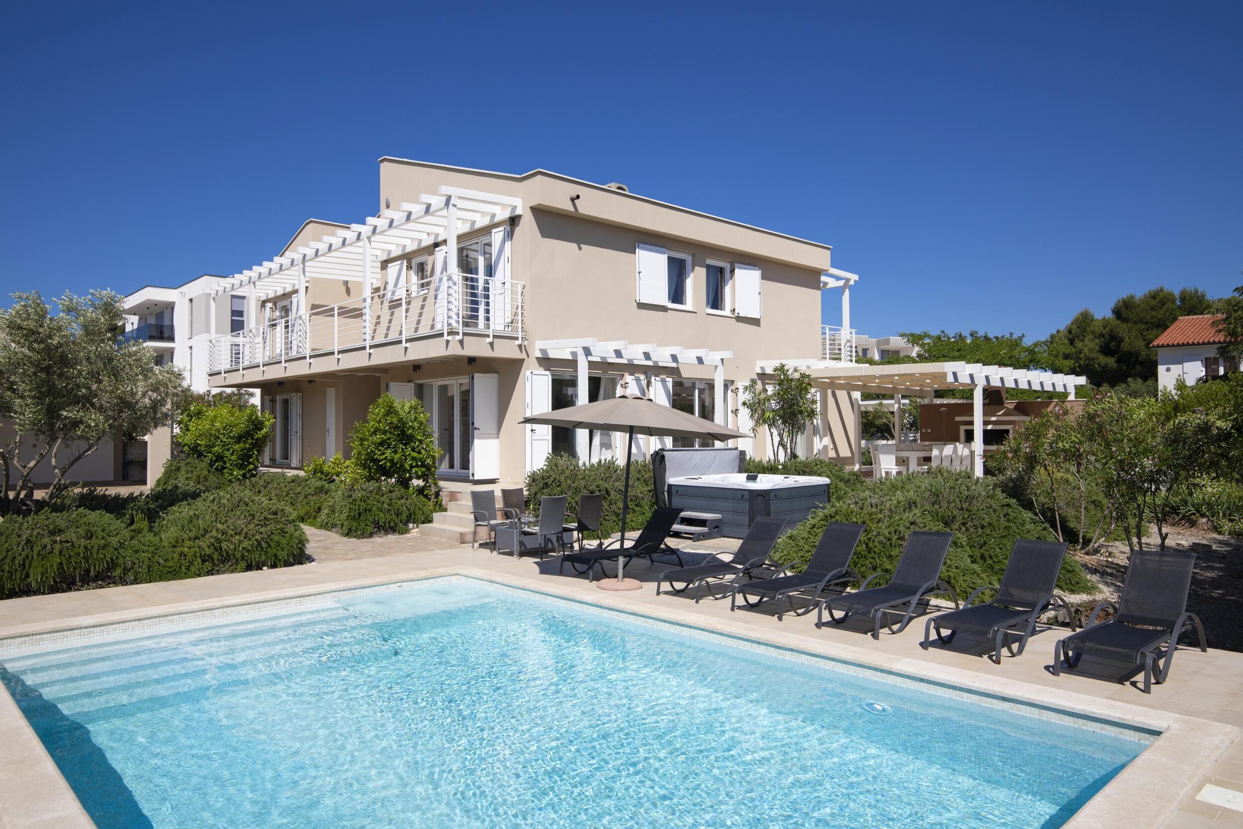 A modern two-story building with a swimming pool, outdoor seating, and a covered patio area.