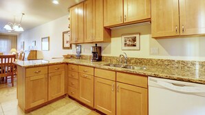 A kitchen with wooden cabinets, granite countertops, a coffee maker, and a dishwasher. - Beautiful Home with views of Lake Dillon, 727B (Frisco)