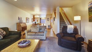 A spacious living room with a sofa, a coffee table, a leather armchair, and a staircase leading to another level. - Beautiful Home with views of Lake Dillon, 727B (Frisco)