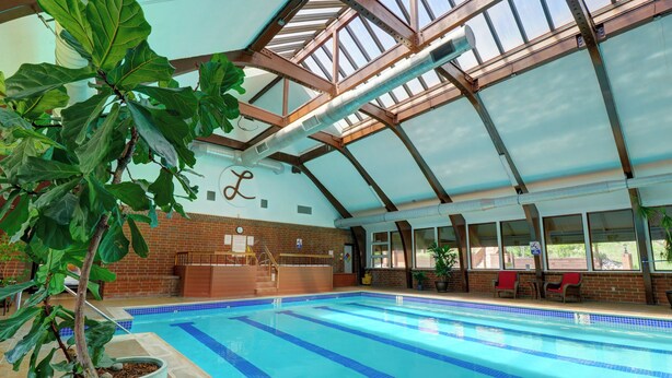 An indoor swimming pool with clear blue water, surrounded by a brick wall and a glass roof. - Beautiful Home with views of Lake Dillon, 727B (Frisco)
