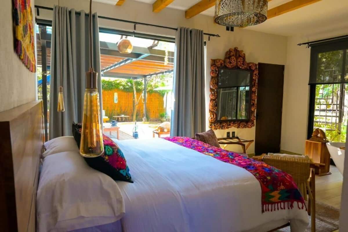 Um quarto espaçoso com uma cama grande, um espelho decorativo e vista para a área externa.