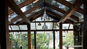 A wooden interior with a glass ceiling, a hanging light fixture, and a view of greenery outside. - Hotel Boutique La Casa Del Lago (Tzintzuntzan)