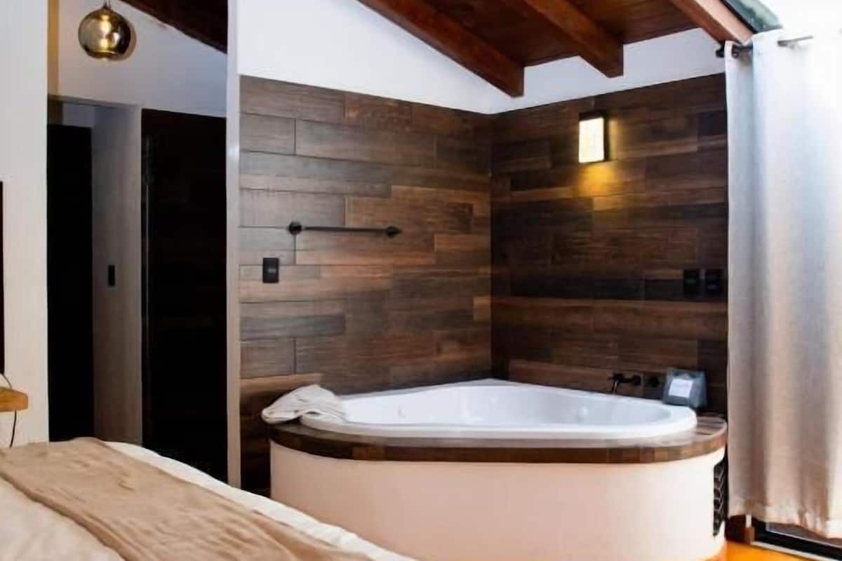 Uma casa de banho moderna com teto de madeira, uma banheira grande e um claraboia.