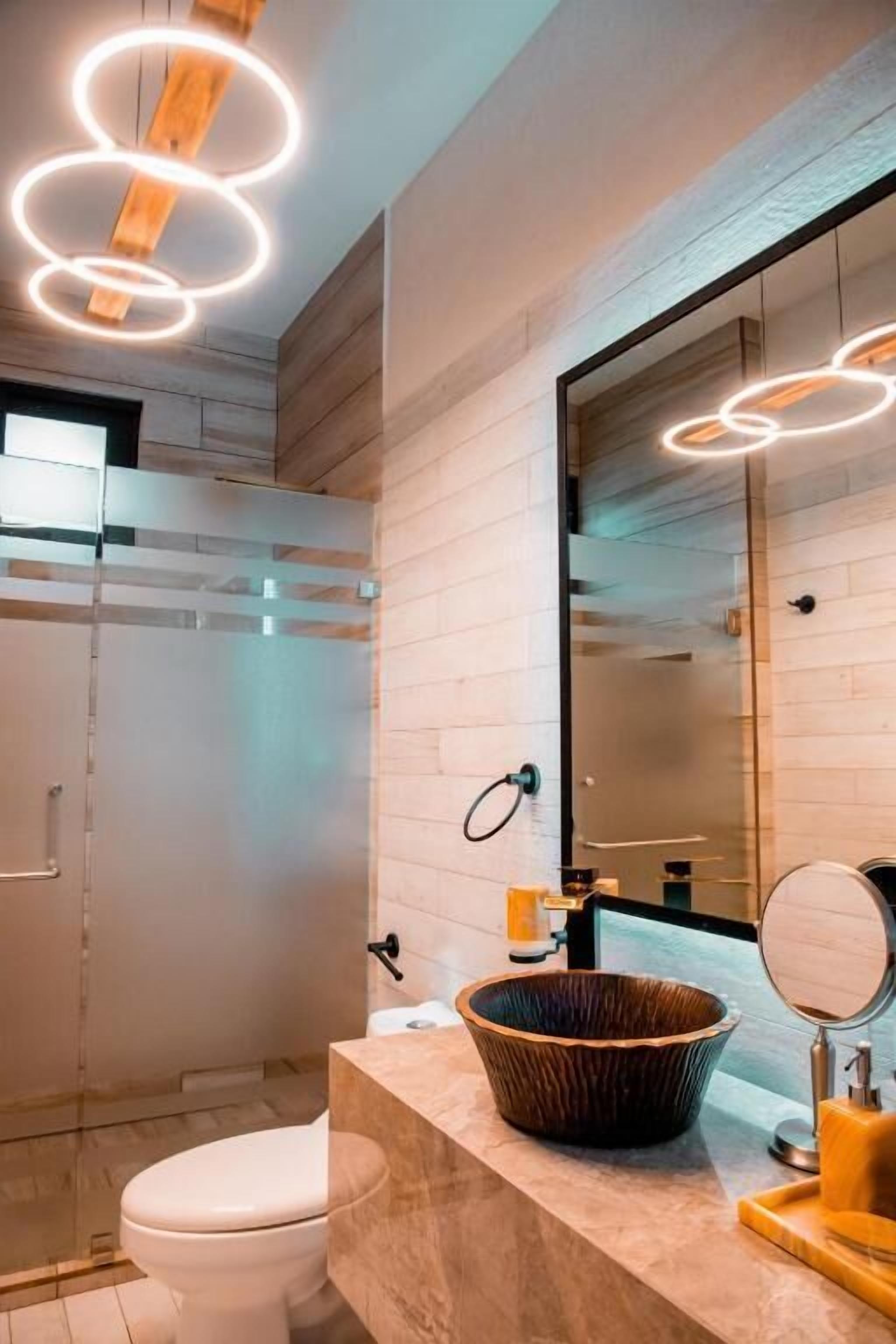 A modern bathroom with a wooden vanity, a large mirror, and a glass shower enclosure.