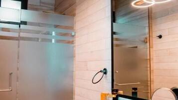 A modern bathroom with a wooden vanity, a large mirror, and a glass shower enclosure.