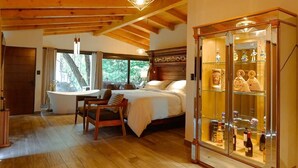 A bedroom with a wooden ceiling, a bed, a glass cabinet with bottles, and a dining area with a table and chairs. - Hotel Boutique La Casa Del Lago (Tzintzuntzan)