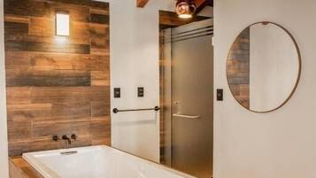 A modern bathroom with a wooden vanity, a freestanding bathtub, and a large mirror on the wall.