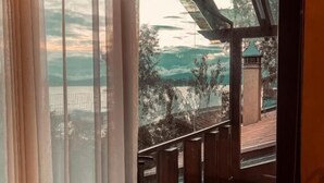 A room with a large window overlooking a deck and a scenic view of hills and a body of water. - Hotel Boutique La Casa Del Lago (Tzintzuntzan)