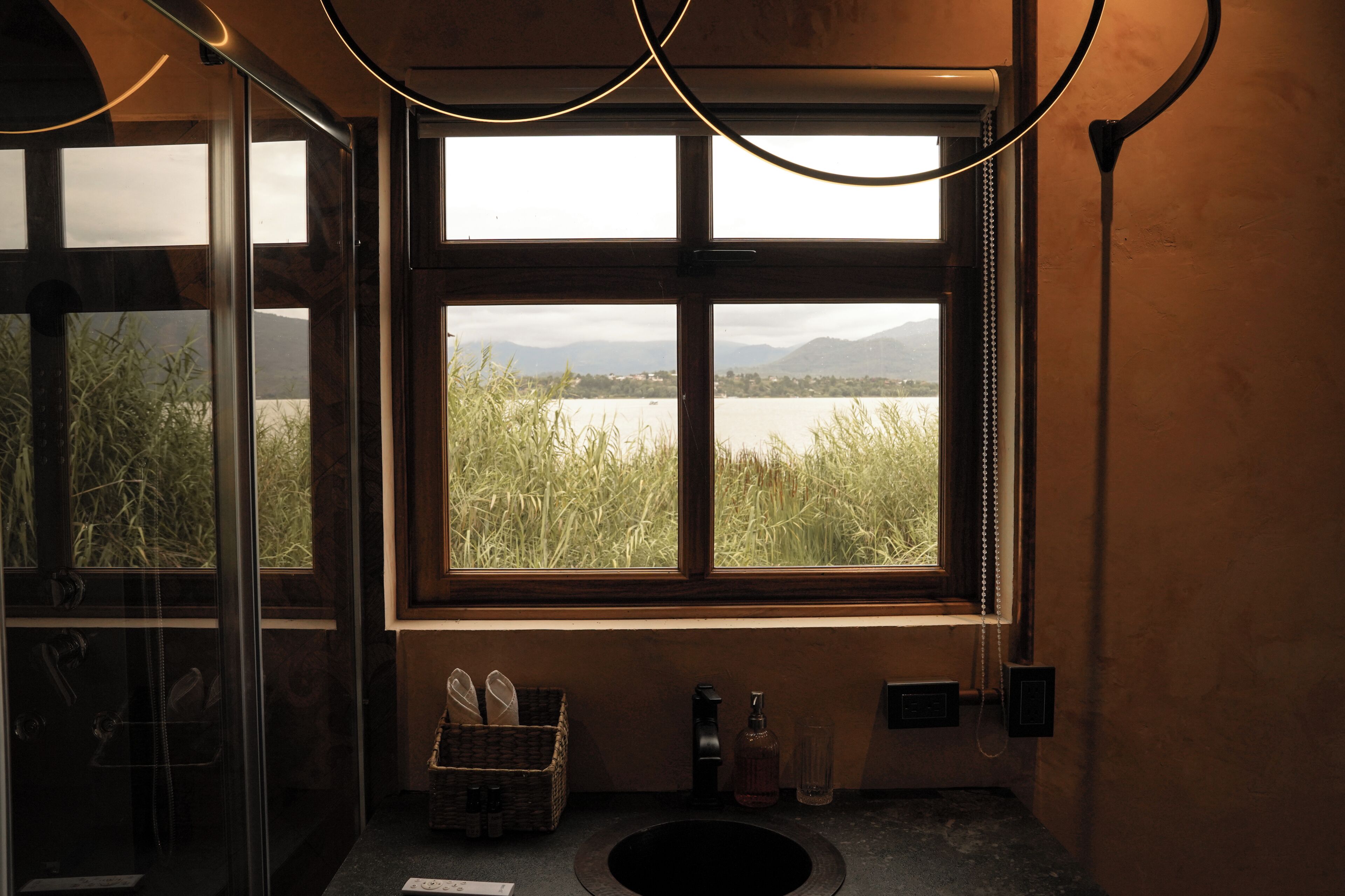 Ein Badezimmer mit einem großen Fenster, einem Waschbecken und einem Tablett mit Pflegeprodukten.