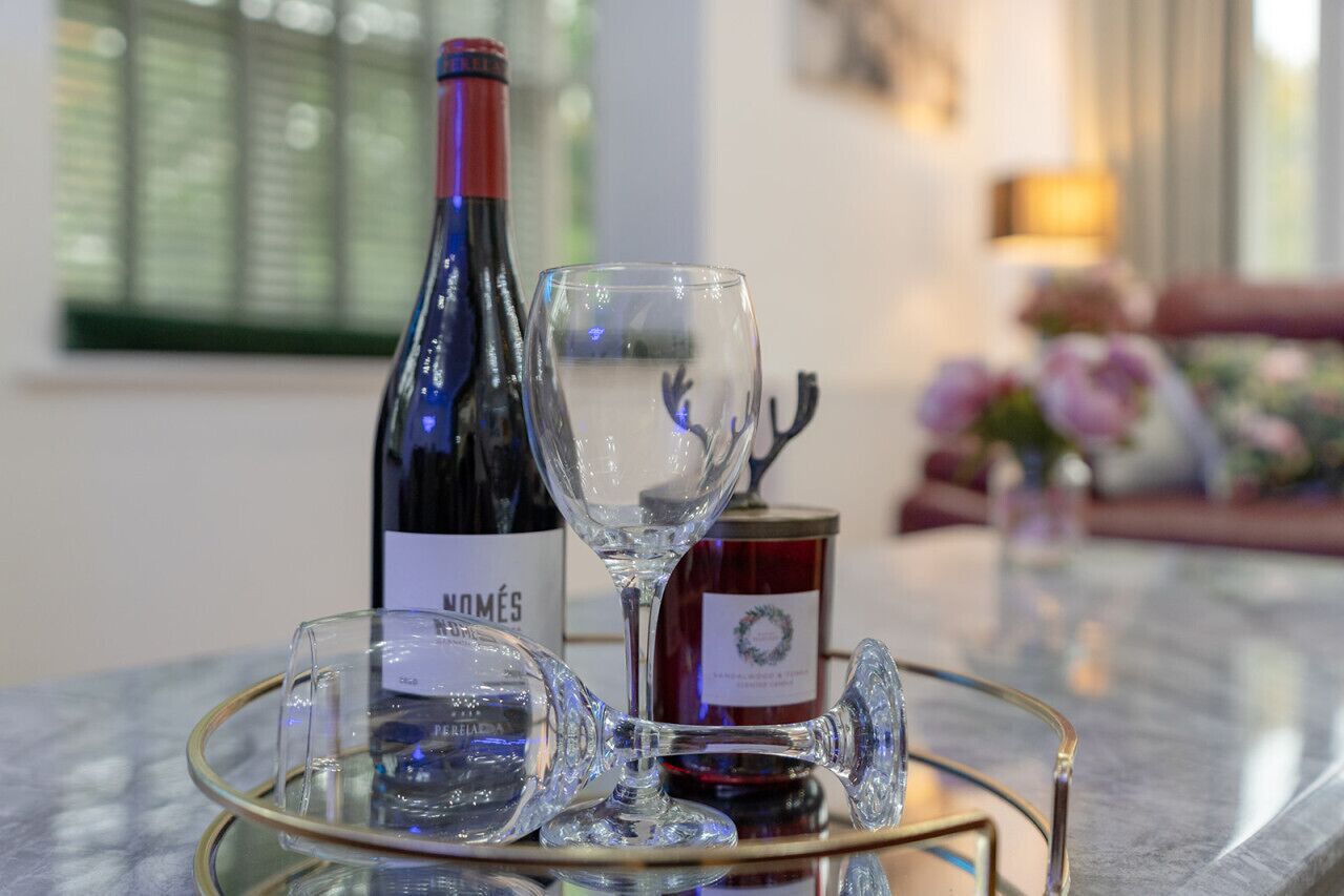 A wine bottle and glasses on a table with a decorative item in the background.