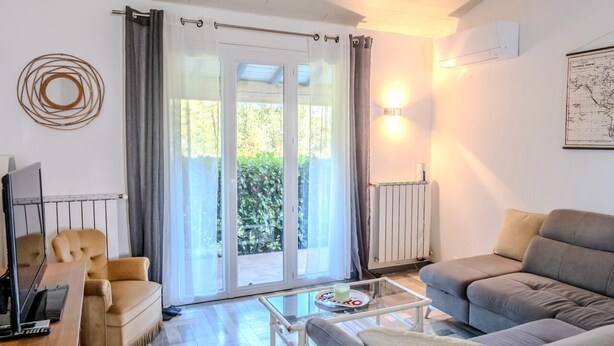 A modern living room with a sofa, armchair, and a coffee table. There is a sliding glass door leading to a garden. - La Pinède, a welcoming family home, 5 minutes from Vallon Pont D'Arc (salavas)