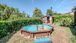 A wooden swimming pool with a ladder, surrounded by lush greenery and a small wooden structure in the background. - La Pinède, a welcoming family home, 5 minutes from Vallon Pont D'Arc (salavas)