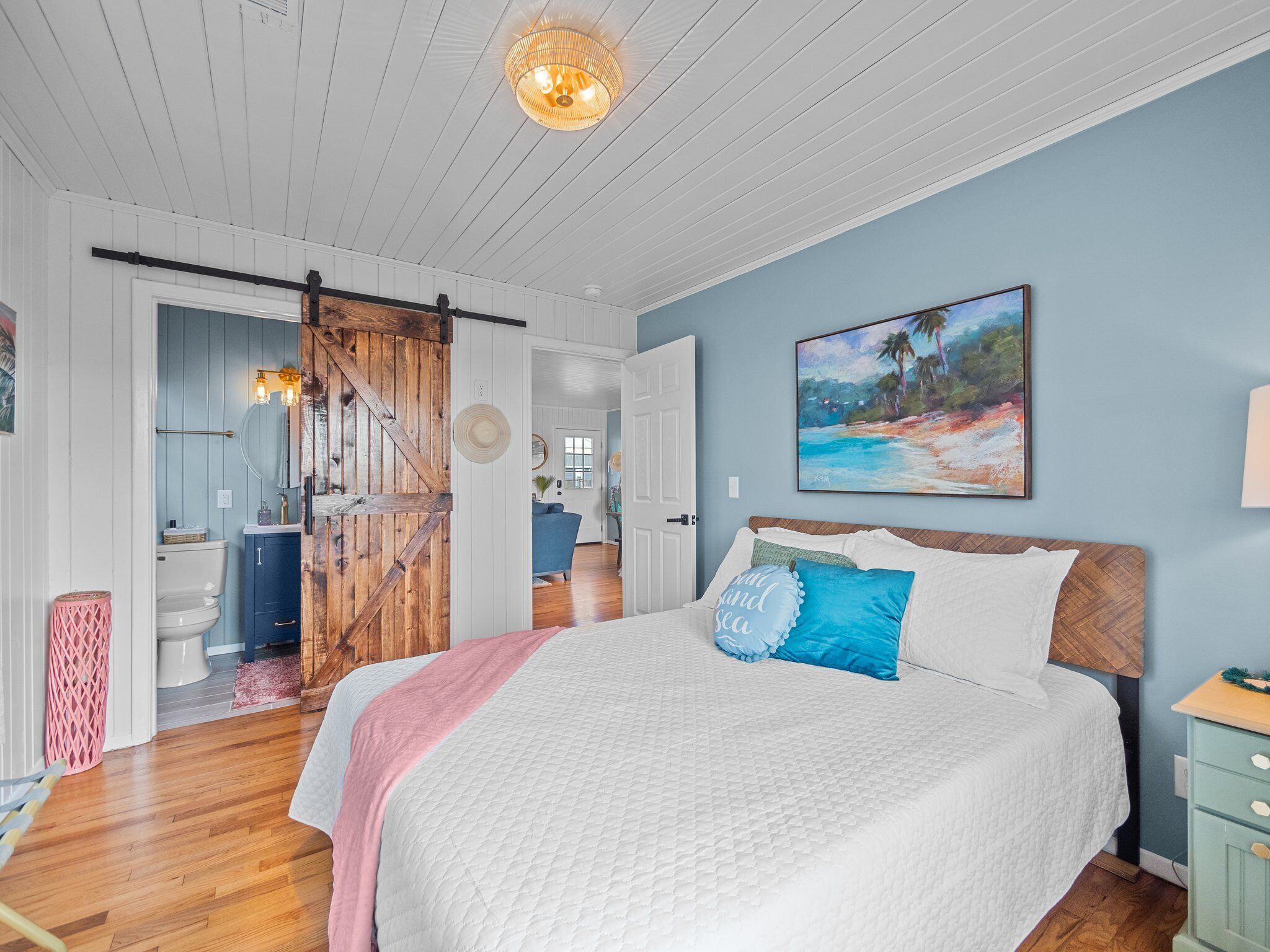 Un dormitorio con una cama, un cuadro y una puerta de madera.