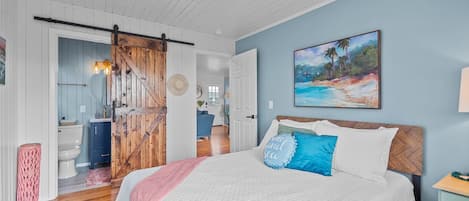 Un dormitorio con una cama, un cuadro y una puerta de madera.