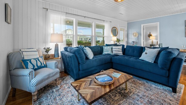 A living room with a blue sectional sofa, striped armchair, and a wooden coffee table.